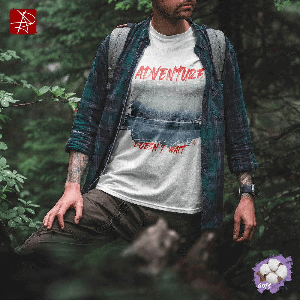 Unisex organic cotton t-shirt with 'Adventure Doesn't Wait' design over snowy lake scene, worn by a person in nature.