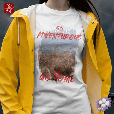 Unisex organic cotton t-shirt with 'Go Adventurous or Go Home' graphic design in mountain grassland setting.