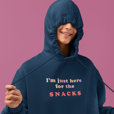 Person wearing SNACKS organic cotton hoodie with quirky text, showcasing eco-friendly unisex fashion.